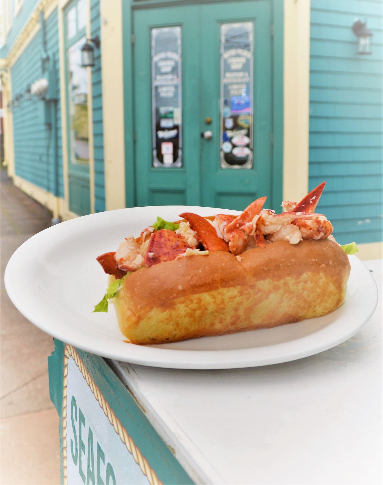 Fresh lobster roll served at the front door of the sea-blue Water Prince Corner Shop